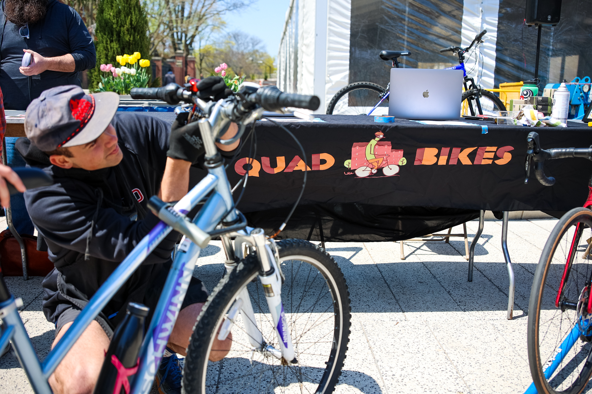 A member of the Quad Bikes student grant project helps fix a student's bike during an Earth Day celebration.