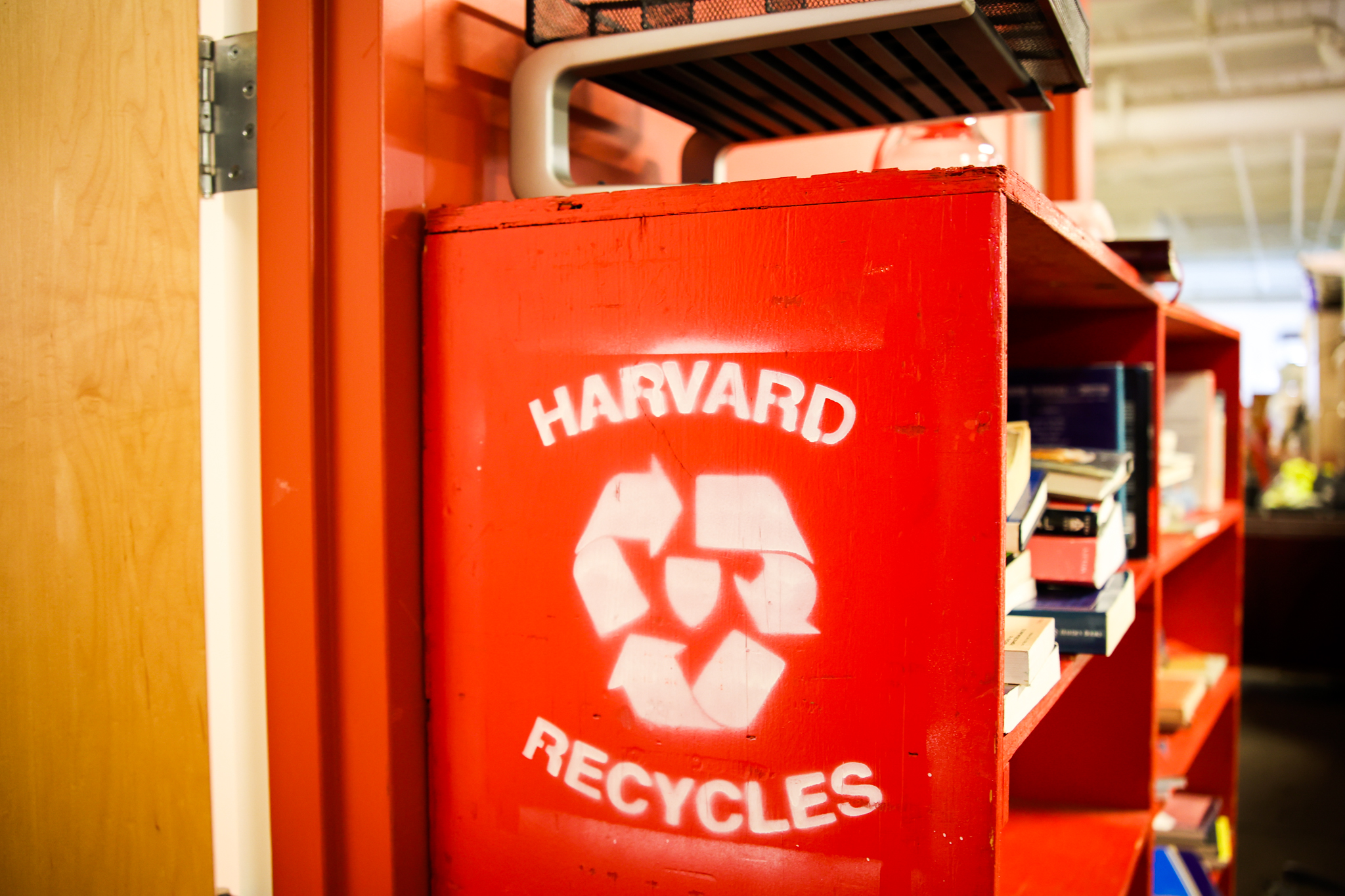 "Harvard Recycles" sign on a red bookshelf.