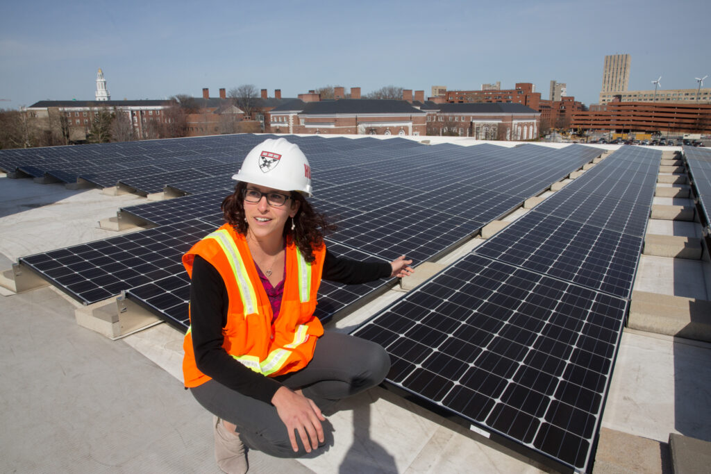 On the roof of Batten Hall, HBS’s energy/sustainability coordinator, Julia Musso, shows a field of solar panels that are framed by the Harvard Business School campus and Harvard Stadium.