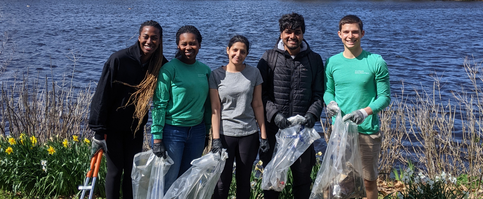 Students pose for photo with bags of trash during the 2022 Charles River Clean-Up.