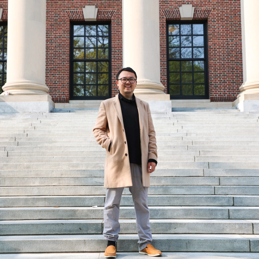 Charles Hua, a Harvard undergraduate student in the class of 2023, smiles while posing for a photo on the steps of the Widener Library.