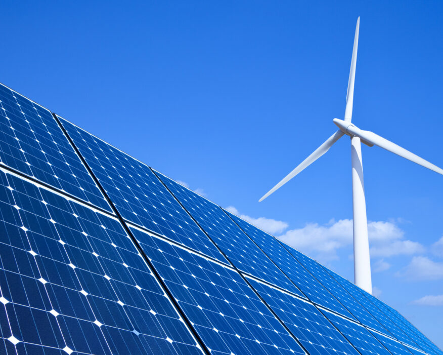 Solar panels and wind turbine against blue sky