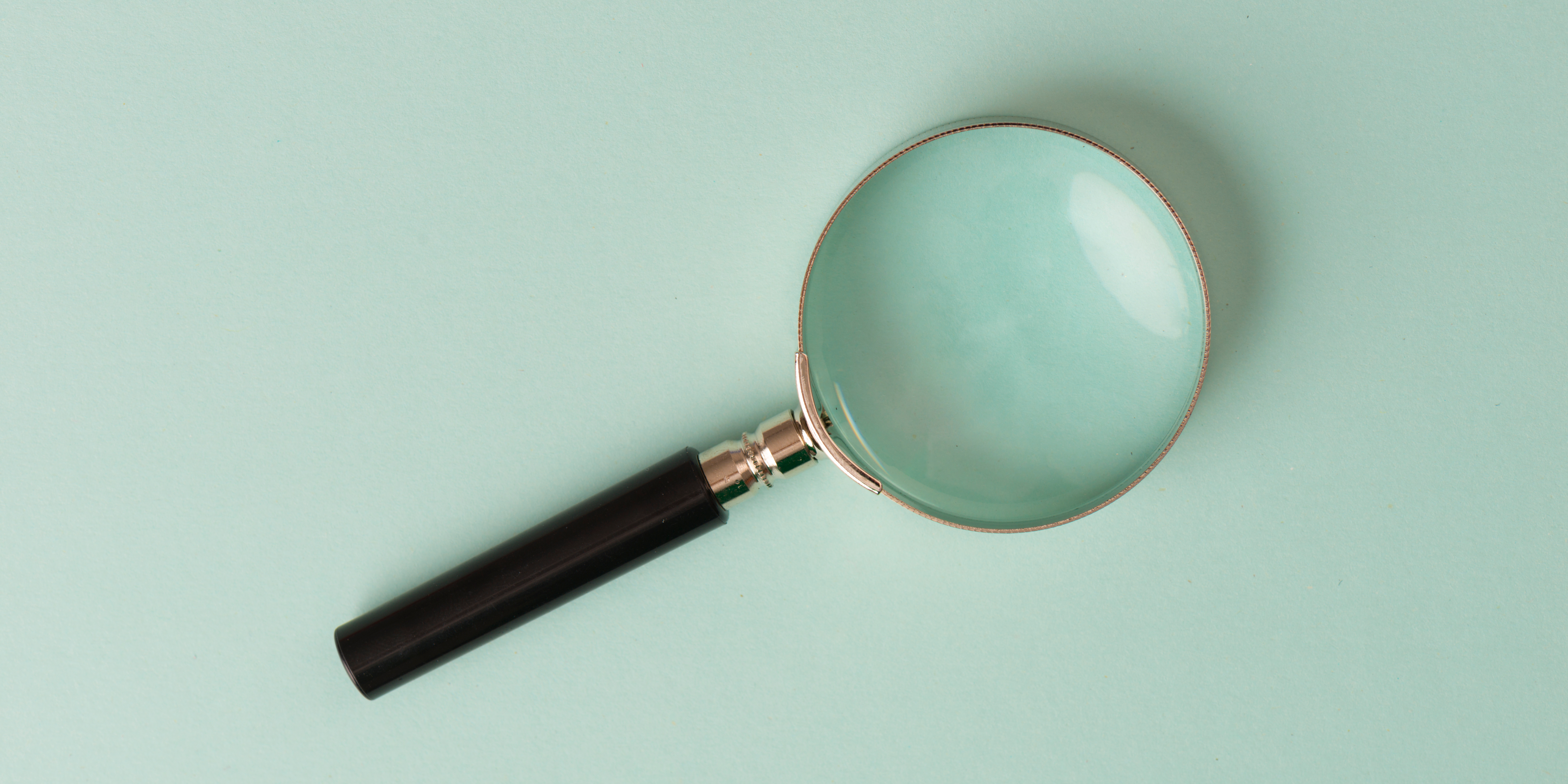Magnifying glass against a green background.